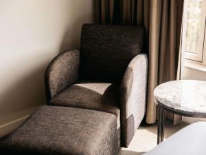 una silla en una habitación con mesa en Mercure Sydney Parramatta, en Sídney