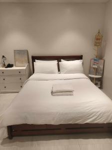 a bedroom with a large white bed and a dresser at El Paseo Tambuli in Maribago