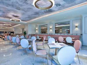 ein Restaurant mit weißen Tischen und rosa Stühlen in der Unterkunft Mercure Hangzhou Xixi Zijingang in Hangzhou