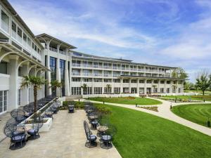 an exterior view of a building with chairs and a lawn at Mövenpick Balaland Resort Lake Balaton in Szántód