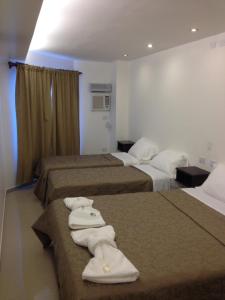 Una habitación de hotel con tres camas y toallas. en Lorenzo Suites Hotel, en San Miguel de Tucumán