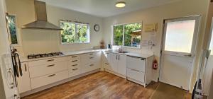a kitchen with white cabinets and white appliances at Soggy Bottom Farm House, Sea views and peacocks in Pakawau