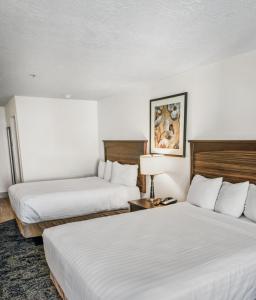 two beds in a hotel room with white sheets at Crystal Inn Hotel & Suites - Salt Lake City in Salt Lake City