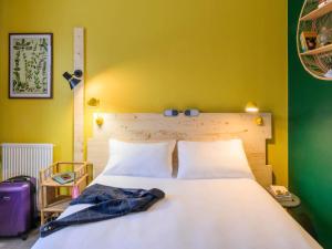 a bedroom with a white bed with a yellow wall at Greet Hotel Evreux Centre - Route de Normandie by Accor in Évreux