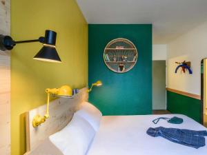 a bedroom with a bed with a yellow and green wall at Greet Hotel Evreux Centre - Route de Normandie by Accor in Évreux