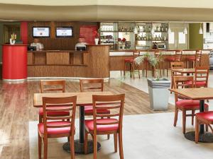 a restaurant with wooden tables and red chairs at Ibis Monterrey Aeropuerto in Monterrey