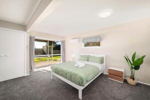 a white bedroom with a bed and a window at 5 Bedrooms Lake View Cosy Place in Rotorua