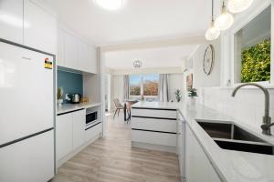 a white kitchen with a sink and a refrigerator at 5 Bedrooms Lake View Cosy Place in Rotorua