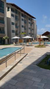 a large building with a pool and tables and umbrellas at Flat na Praia dos Carneiros a 250m do mar in Tamandaré