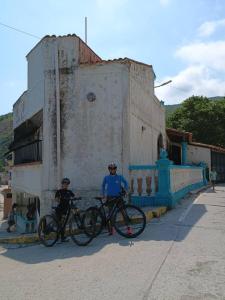 two people standing with their bikes in front of a building at Casa Cerdeña in Puerto Carayaca