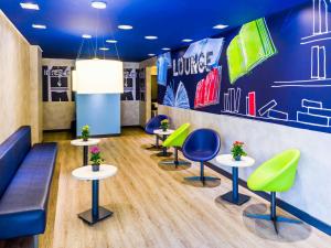 a waiting room with green and blue chairs and tables at ibis budget Sao Paulo Jardins in Sao Paulo
