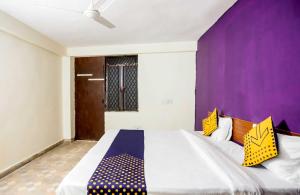 a bedroom with a large bed with a purple wall at SPOT ON Hotel Harry's 1 Near Select Citywalk Mall in New Delhi