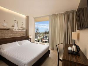 a bedroom with a bed and a window with a sailboat on the wall at Mercure Rimini Lungomare in Rimini