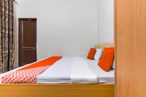 a bedroom with a bed with orange pillows on it at Hotel O Sabtera Homes in Kharar +32 photos