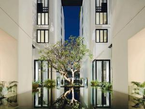 un árbol en el medio de un edificio con ventanas en Mövenpick Hotel Sukhumvit 15 Bangkok, en Bangkok