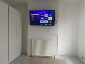 a flat screen tv hanging on a wall with a radiator at 3 Bed House in Reading Area in Reading