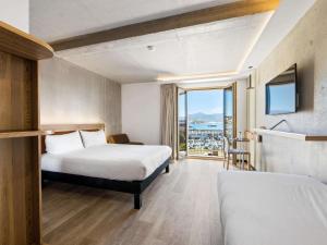 Una habitación de hotel con dos camas y balcón. en ibis Styles Ajaccio Napoleon, en Ajaccio 75 fotos más
