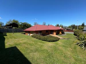 a house with a red roof in a yard at 4 St James Avenue in Hanmer Springs