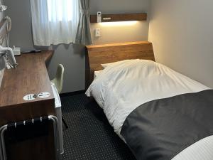 一関市にあるアットビジネスホテル一関のベッドと机のある小さな寝室