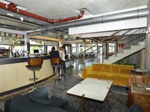 Un vestíbulo con un bar con un sofá amarillo. en ibis Styles Ajaccio Napoleon, en Ajaccio