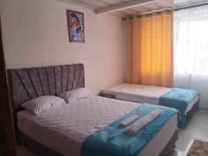 a bedroom with two beds and a couch and a window at AMAZONIKA Casa de Huespedes in Inírida +2 photos
