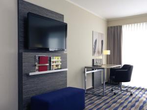 a hotel room with a desk and a flat screen tv at Mercure Hotel am Entenfang Hannover in Hannover +46 photos