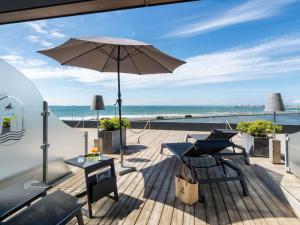 Un patio con sombrilla, mesas y sillas. en Côte Ouest Thalasso & Spa Les Sables d'Olonne - MGallery Collection, en Les Sables-dʼOlonne