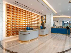 two people standing at a counter in a restaurant at Mövenpick Living West Hanoi in Hanoi