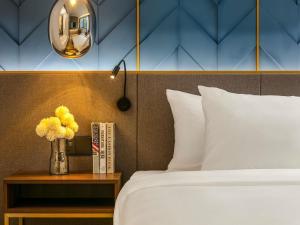 a bedroom with a bed and a vase of flowers on a table at Mövenpick Living West Hanoi in Hanoi