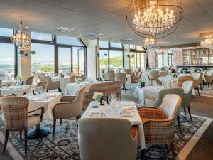 Un restaurante con mesas, sillas y lámparas de araña. en Côte Ouest Thalasso & Spa Les Sables d'Olonne - MGallery Collection, en Les Sables-dʼOlonne