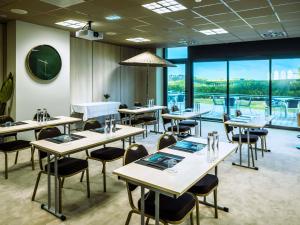 Un restaurante con mesas y sillas y grandes ventanales. en Côte Ouest Thalasso & Spa Les Sables d'Olonne - MGallery Collection, en Les Sables-dʼOlonne 118 fotos más
