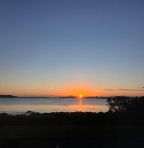 a sunset over a body of water with the sun setting at Auckland Sunrise Sea View in Auckland