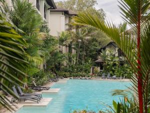 einen Pool in einem Resort mit Liegestühlen und Palmen in der Unterkunft Pullman Palm Cove Sea Temple Resort & Spa in Palm Cove