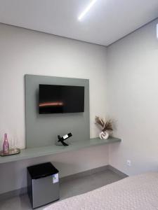 Habitación con TV en una pared blanca en Pousada Vista do Voo, en Brumadinho