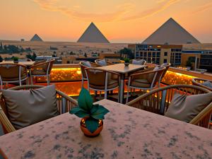 a view of the pyramids from a restaurant with a table at 3 PYRAMiDS HUT HOTEL in Cairo