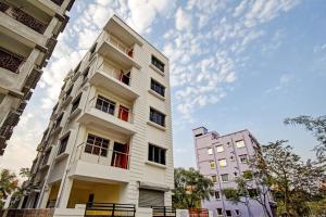 a white building with red windows in a city at Super Hotel O Shree Residency in Thākurdwari