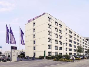 a white building with flags in front of it at Mercure Hotel Frankfurt Eschborn Ost in Eschborn