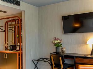 a room with a desk with a television on the wall at MUZE Hotel Dusseldorf - Handwritten Collection in Düsseldorf