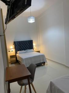 a bedroom with a bed and a table and a chair at Hotel Raymondi in Tarapoto +8 photos