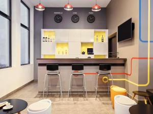 a bar in a restaurant with stools and clocks on the wall at ibis Styles Marseille Gare Saint-Charles in Marseille