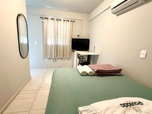1 dormitorio con 1 cama verde y TV en Pousada da Laís, en Blumenau