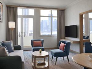 a living room with a couch and chairs and a tv at Swissôtel Al Murooj Dubai in Dubai