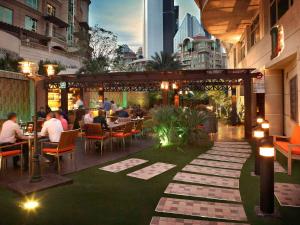 a restaurant with people sitting at tables on a patio at Swissôtel Al Murooj Dubai in Dubai +188 photos