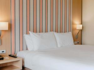 ein Bett mit weißen Kissen in einem Hotelzimmer in der Unterkunft Mercure Gold Coast Resort in Gold Coast