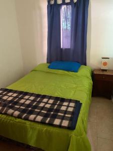a bedroom with a green bed with a window at Casita de los recuerdos in Villa Carlos Paz