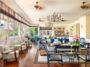 a living room with blue furniture and windows at Raffles Grand Hotel d'Angkor in Siem Reap