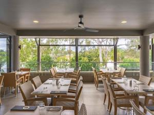 a dining room with tables and chairs and windows at Mercure Rockhampton in Rockhampton
