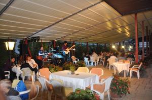 um grupo de pessoas sentadas em mesas em um restaurante em Hotel Melis em Balatonlelle