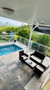 a patio with a table and chairs and a pool at Panorama180 in Le Marin