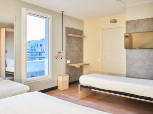 Una habitación de hotel con dos camas y una ventana. en ibis budget Issy Les Moulineaux Paris Ouest, en Issy-les-Moulineaux 79 fotos más